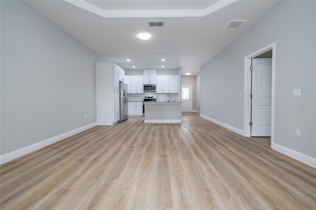47 Providence Ln, Palm Coast, FL 32164 - kitchen featuring appliances with stainless steel finishes, open floor plan, light wood finished floors, white cabinetry, and light countertops