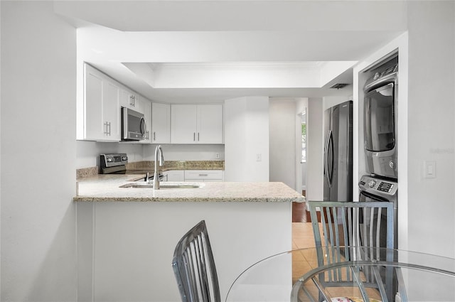 8 Oakmont Ct Unit 0, Palm Coast, FL 32137 - kitchen featuring appliances with stainless steel finishes, stacked washer / drying machine, a sink, a peninsula, and white cabinets
