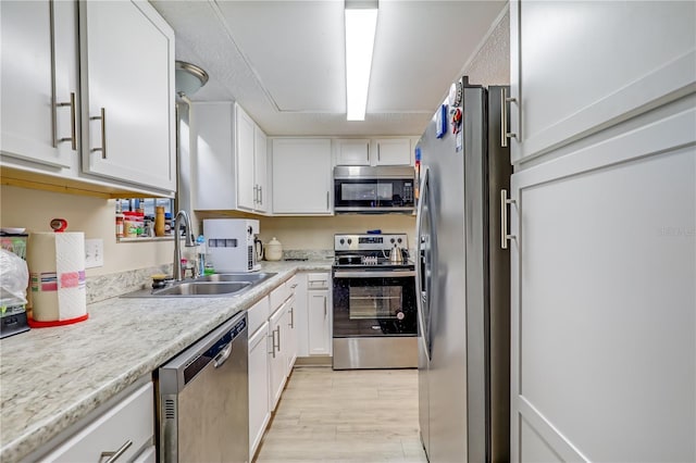 503 Kettering Way, Orange Park, FL 32073 - kitchen with appliances with stainless steel finishes, a sink, light wood-style floors, white cabinets, and light countertops
