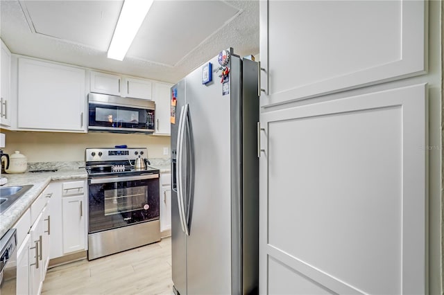 503 Kettering Way, Orange Park, FL 32073 - kitchen with stainless steel appliances, white cabinetry, light wood-type flooring, light stone counters, and a sink