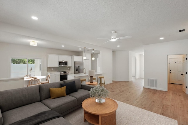 40 Pinetree Dr, Palm Coast, FL 32164 - living room featuring ceiling fan, light wood-type flooring, recessed lighting, a textured ceiling, and arched walkways