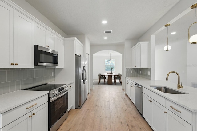 40 Pinetree Dr, Palm Coast, FL 32164 - kitchen with stainless steel appliances, a sink, arched walkways, white cabinets, and recessed lighting