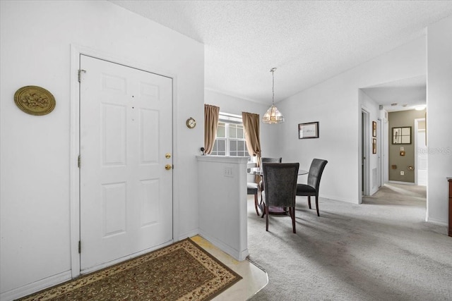 19 Utica Path, Palm Coast, FL 32164 - foyer with a chandelier, vaulted ceiling, light carpet, a textured ceiling, and baseboards