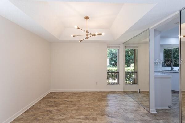 9 Masters Ct, Palm Coast, FL 32137 - spare room featuring a tray ceiling, a chandelier, and baseboards