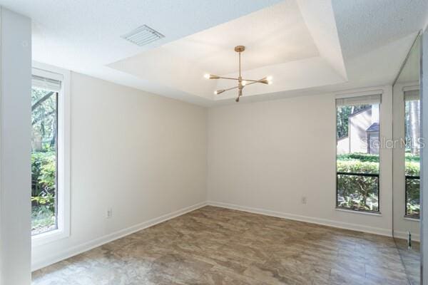 9 Masters Ct, Palm Coast, FL 32137 - empty room with a raised ceiling, a chandelier, and baseboards