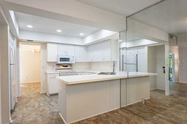 9 Masters Ct, Palm Coast, FL 32137 - kitchen with white appliances, a raised ceiling, a sink, white cabinetry, and recessed lighting