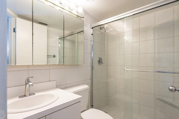 9 Masters Ct, Palm Coast, FL 32137 - full bathroom featuring toilet, a stall shower, vanity, and tile walls