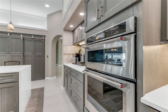21 Webster Ln, Palm Coast, FL 32164 - kitchen with stainless steel double oven, gray cabinets, arched walkways, decorative backsplash, and light countertops
