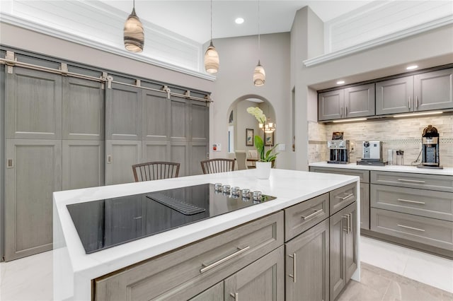 21 Webster Ln, Palm Coast, FL 32164 - kitchen featuring black electric cooktop, a high ceiling, backsplash, gray cabinets, and arched walkways
