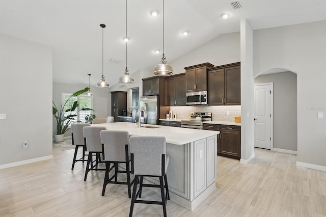 70 Esperanto Dr, Palm Coast, FL 32164 - kitchen with stainless steel appliances, arched walkways, a kitchen island with sink, a kitchen breakfast bar, and dark brown cabinetry
