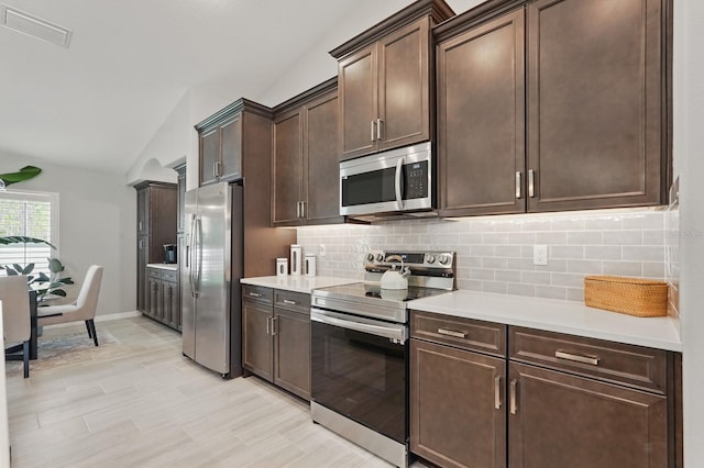 70 Esperanto Dr, Palm Coast, FL 32164 - kitchen featuring appliances with stainless steel finishes, decorative backsplash, light countertops, vaulted ceiling, and dark brown cabinetry