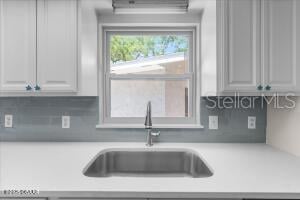 4901 Sailfish Dr, Ponce Inlet, FL 32127 - kitchen featuring a sink, light countertops, tasteful backsplash, and a wall mounted air conditioner