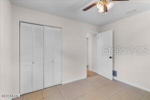 4901 Sailfish Dr, Ponce Inlet, FL 32127 - unfurnished bedroom featuring baseboards, light tile patterned floors, a closet, and ceiling fan