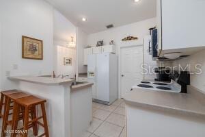54 Price Ln, Palm Coast, FL 32164 - kitchen featuring freestanding refrigerator, a kitchen bar, a peninsula, light tile patterned floors, and stove