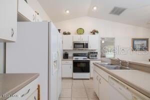 54 Price Ln, Palm Coast, FL 32164 - kitchen with white appliances, vaulted ceiling, white cabinetry, light tile patterned floors, and recessed lighting