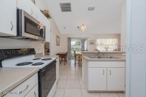 54 Price Ln, Palm Coast, FL 32164 - kitchen with electric range oven, stainless steel microwave, a sink, white cabinets, and light countertops