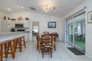 54 Price Ln, Palm Coast, FL 32164 - dining room featuring lofted ceiling, a chandelier, and light tile patterned floors