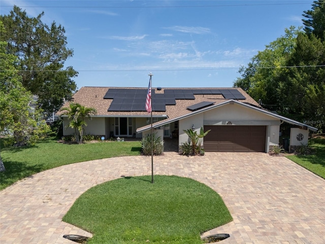 9 Cotton Ct, Palm Coast, FL 32137 - ranch-style house with a front lawn, decorative driveway, a garage, solar panels, and roof with shingles
