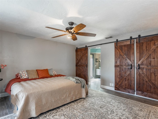 9 Cotton Ct, Palm Coast, FL 32137 - bedroom featuring a barn door, wood finished floors, baseboards, and connected bathroom