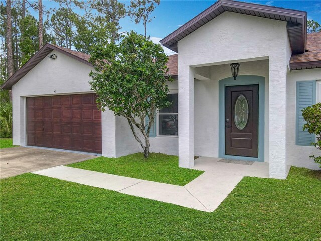14 Zollinger Pl, Palm Coast, FL 32164 - view of front facade featuring stucco siding, a front lawn, and an attached garage