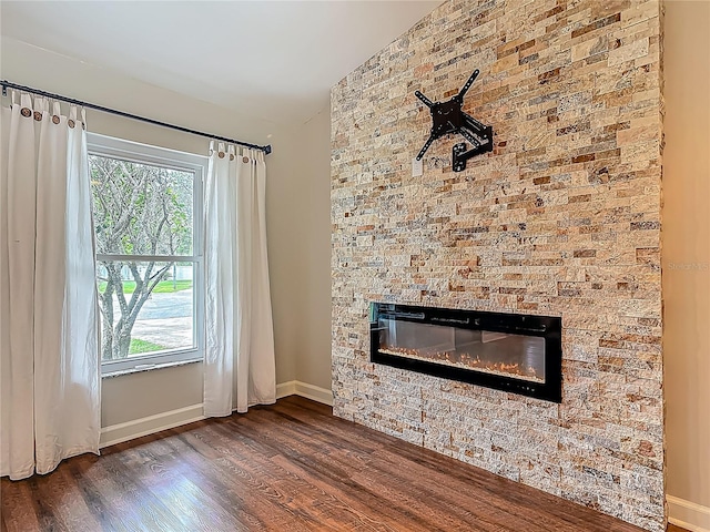 14 Zollinger Pl, Palm Coast, FL 32164 - unfurnished living room featuring a glass covered fireplace, dark wood-style floors, and baseboards