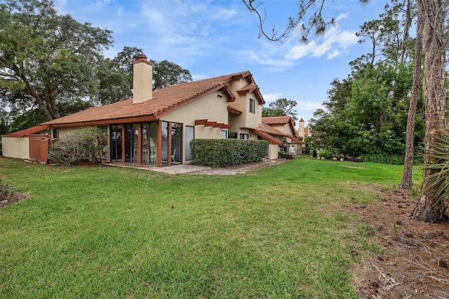 55 Village Cir, Palm Coast, FL 32164 - back of house featuring a chimney, stucco siding, a sunroom, a yard, and a tile roof
