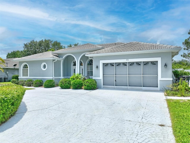 80 Flemingwood Ln, Palm Coast, FL 32137 - mediterranean / spanish-style house featuring a garage, decorative driveway, a tiled roof, and stucco siding