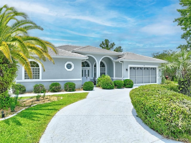 80 Flemingwood Ln, Palm Coast, FL 32137 - mediterranean / spanish-style house featuring an attached garage, stucco siding, a tile roof, and driveway