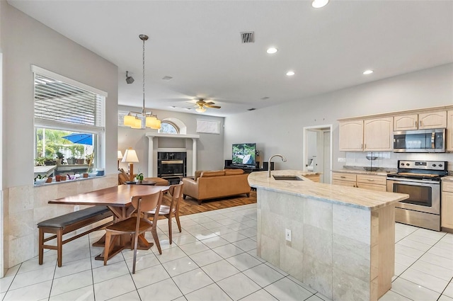 80 Flemingwood Ln, Palm Coast, FL 32137 - kitchen with appliances with stainless steel finishes, light brown cabinets, a tiled fireplace, light tile patterned flooring, and ceiling fan