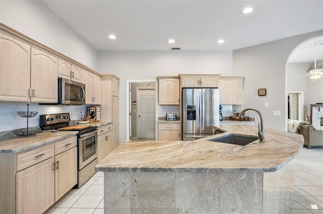 80 Flemingwood Ln, Palm Coast, FL 32137 - kitchen featuring stainless steel appliances, light brown cabinetry, a sink, recessed lighting, and arched walkways