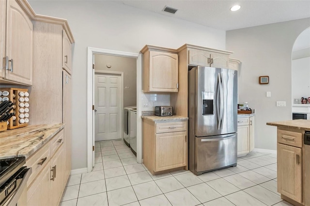 80 Flemingwood Ln, Palm Coast, FL 32137 - kitchen with appliances with stainless steel finishes, light brown cabinets, washer and clothes dryer, arched walkways, and light tile patterned flooring