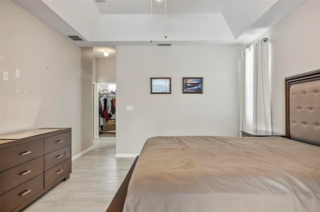 80 Flemingwood Ln, Palm Coast, FL 32137 - bedroom with a tray ceiling, a walk in closet, baseboards, and light wood finished floors