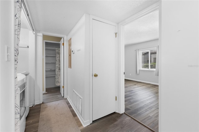 1 Tomoka Oaks Blvd Unit 135, Ormond Beach, FL 32174 - hallway featuring washer and clothes dryer, dark wood-type flooring, a textured ceiling, and baseboards