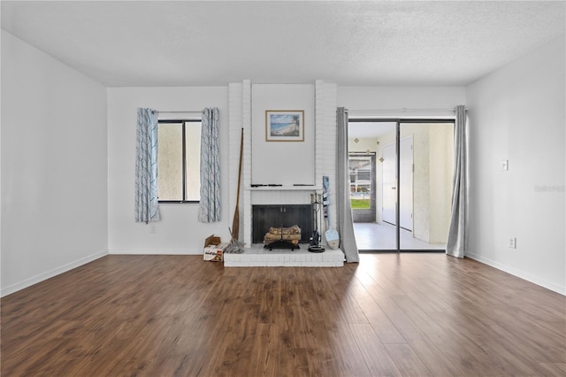 1 Tomoka Oaks Blvd Unit 135, Ormond Beach, FL 32174 - unfurnished living room featuring plenty of natural light, wood finished floors, a brick fireplace, baseboards, and a textured ceiling
