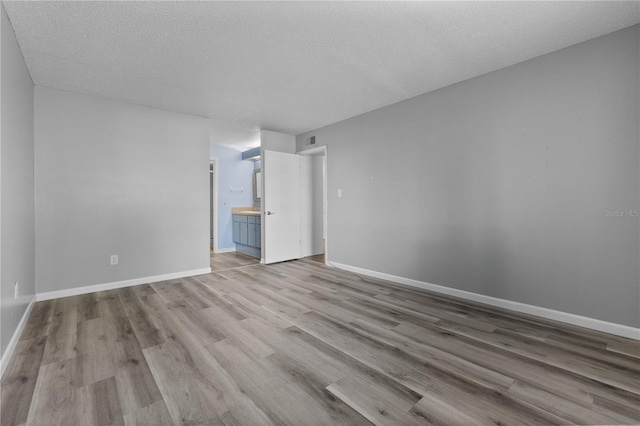 1 Tomoka Oaks Blvd Unit 135, Ormond Beach, FL 32174 - empty room with wood finished floors, a textured ceiling, and baseboards