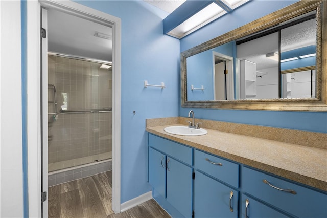 1 Tomoka Oaks Blvd Unit 135, Ormond Beach, FL 32174 - bathroom featuring vanity, wood finished floors, a stall shower, baseboards, and a textured ceiling