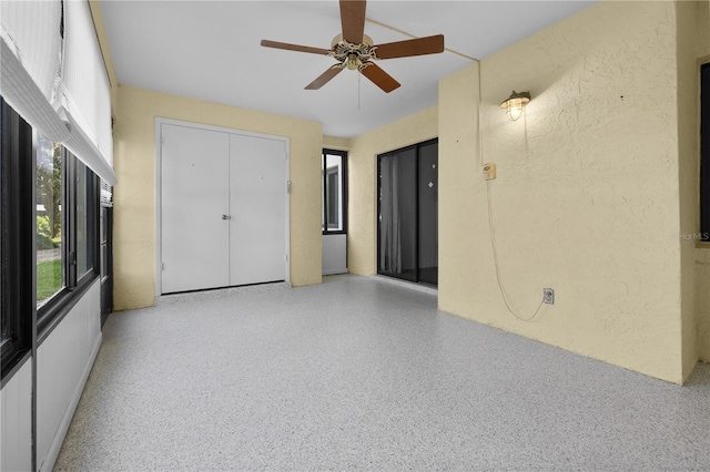 1 Tomoka Oaks Blvd Unit 135, Ormond Beach, FL 32174 - unfurnished bedroom with speckle patterned floor, a textured wall, and a ceiling fan