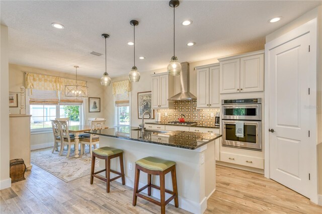 47 Hidden Treasure Dr, Palm Coast, FL 32137 - kitchen featuring wall chimney range hood, stainless steel appliances, a sink, light wood-style flooring, and recessed lighting