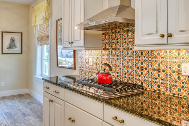47 Hidden Treasure Dr, Palm Coast, FL 32137 - kitchen featuring wall chimney exhaust hood, baseboards, stainless steel gas stovetop, light wood-style flooring, and white cabinetry