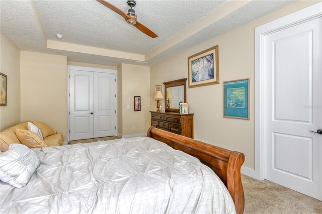 47 Hidden Treasure Dr, Palm Coast, FL 32137 - bedroom featuring a textured ceiling, light colored carpet, baseboards, a closet, and a tray ceiling