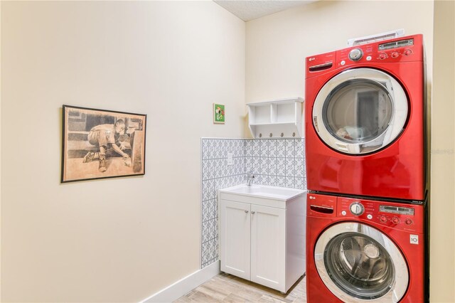 47 Hidden Treasure Dr, Palm Coast, FL 32137 - washroom featuring stacked washer and clothes dryer, cabinet space, light wood finished floors, and baseboards