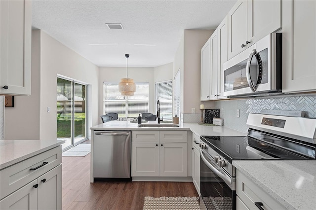 8 Zelda Ct, Palm Coast, FL 32164 - kitchen with appliances with stainless steel finishes, a sink, dark wood-style flooring, a peninsula, and decorative light fixtures