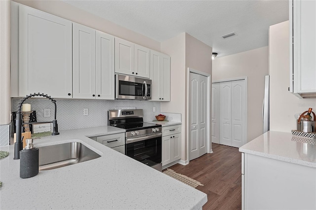 8 Zelda Ct, Palm Coast, FL 32164 - kitchen featuring stainless steel appliances, a sink, white cabinetry, decorative backsplash, and dark wood-style flooring