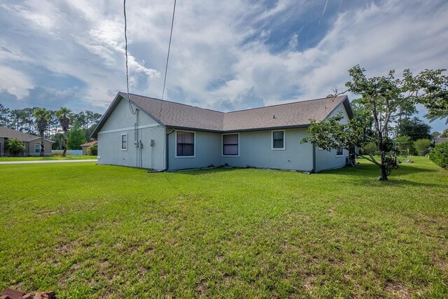 13 Point Of Woods Dr, Palm Coast, FL 32164 - back of property with a lawn and stucco siding