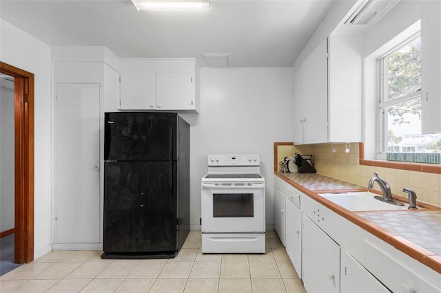 168 Palmetto Ave, Flagler Beach, FL 32136 - kitchen featuring electric range, freestanding refrigerator, a sink, white cabinetry, and light tile patterned floors
