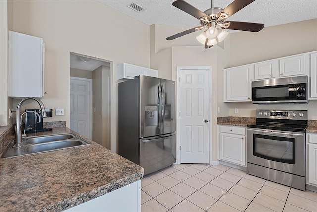 18 Royal Palm Ln, Palm Coast, FL 32164 - kitchen featuring stainless steel appliances, a sink, white cabinets, light tile patterned floors, and a textured ceiling