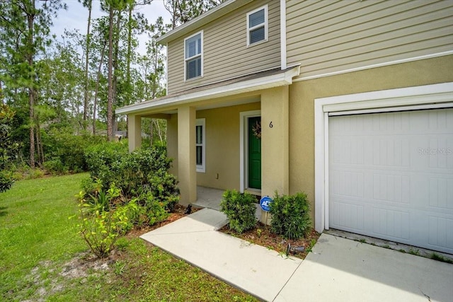 6 Ryding Ln, Palm Coast, FL 32164 - view of exterior entry with a garage, stucco siding, and a lawn