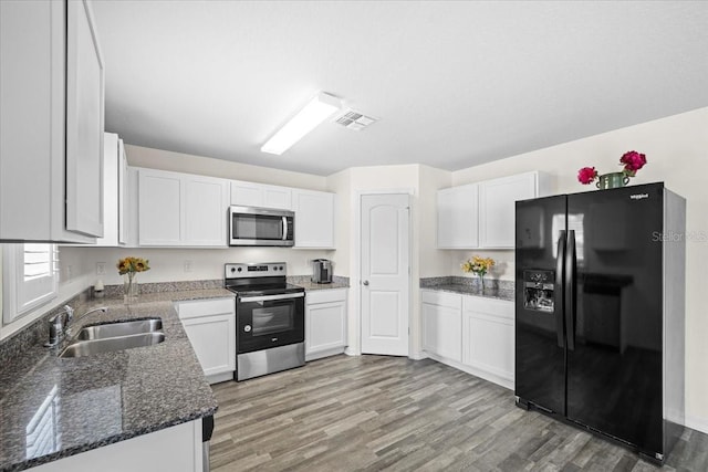6 Ryding Ln, Palm Coast, FL 32164 - kitchen featuring appliances with stainless steel finishes, a sink, light wood-type flooring, white cabinetry, and dark stone countertops