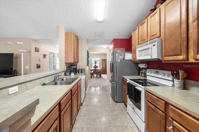33 Bud Field Dr, Palm Coast, FL 32137 - kitchen featuring white appliances, a sink, light countertops, brown cabinets, and a textured ceiling