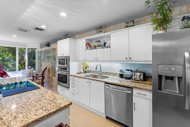 2934 Oceans Trce, Daytona Beach Shores, FL 32118 - kitchen with appliances with stainless steel finishes, open shelves, white cabinetry, a textured ceiling, and light stone countertops